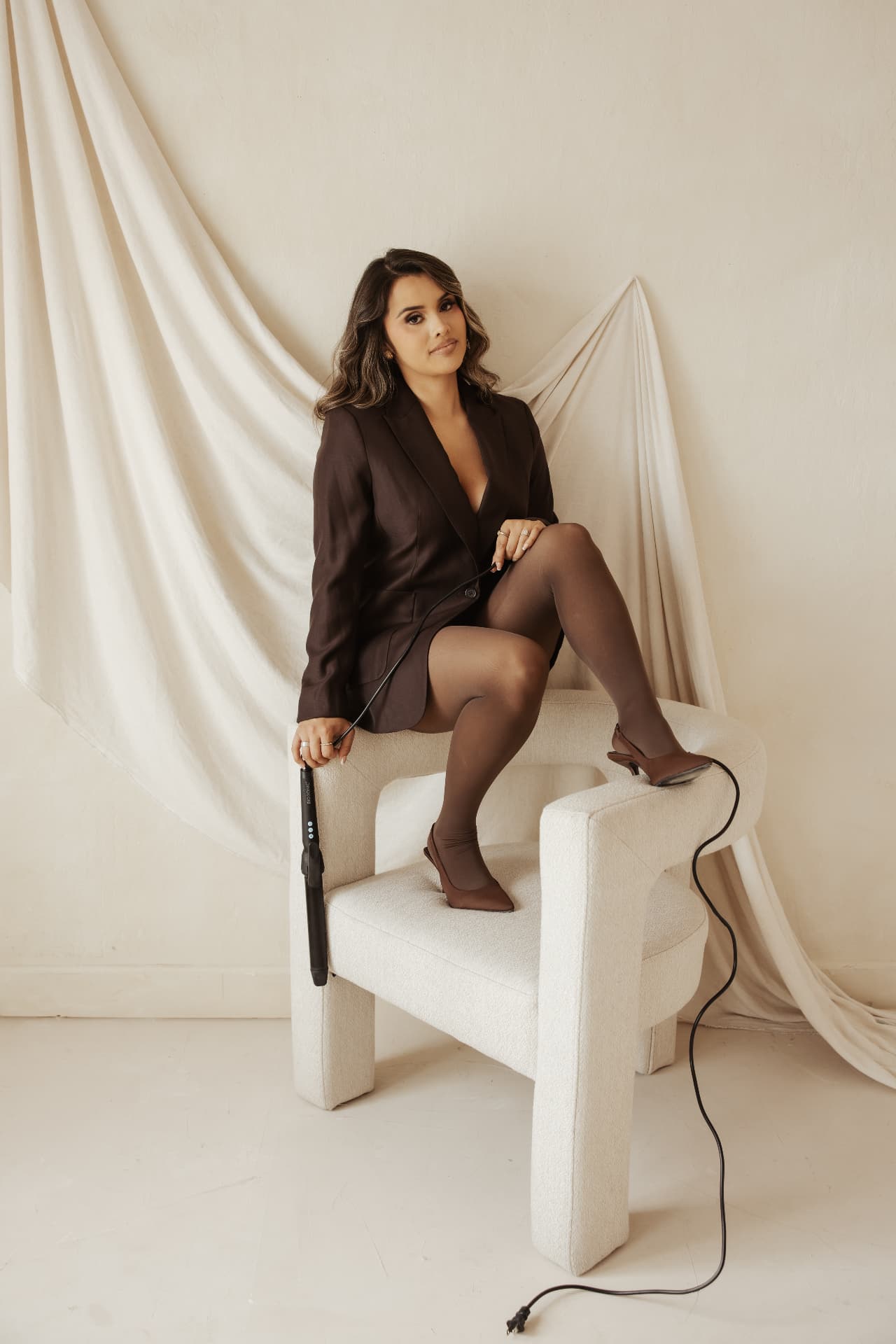 Betty Rey seated with a styling iron in an editorial studio portrait